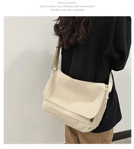 Detailed view of a large cream canvas messenger bag worn by a person in a black shirt
