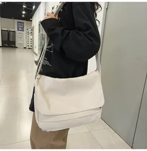Close-up view of a minimalist cream canvas messenger bag in Japanese workwear style
