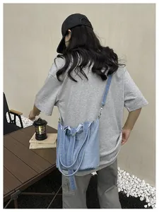 Une vue détaillée d'un élégant sac seau en denim porté en bandoulière dans un cadre extérieur