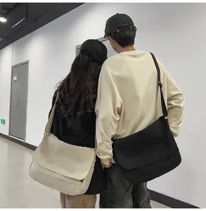 Couple wearing large canvas workwear messenger bags in black and cream colors