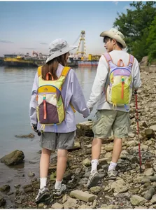 Outdoor-Enthusiasten mit bunten Dopamin-Wanderrucksäcken am Flussufer