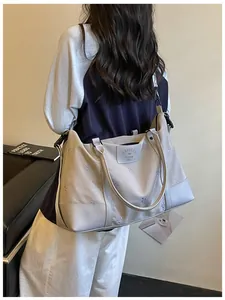 Detailed view of a light grey travel bag with purple bow embroidery shown on a model