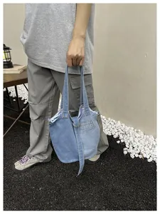 Détail d'un sac seau en jean bleu décontracté avec poignées et sangle décorative à anneau