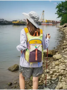 Farbenfroher Dopamin-Outdoor-Wanderrucksack an einer Wanderin am Flussufer gezeigt