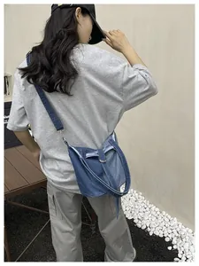 Gros plan d'un sac seau en denim bleu tendance porté en bandoulière par un mannequin