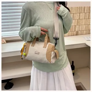 Frau im grünen Shirt trägt eine stylische beige-khakifarbene Pillow-Umhängetasche