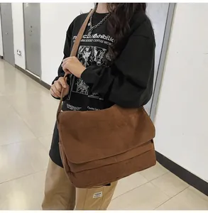Detail showing a large brown corduroy messenger bag worn by a person in an indoor hallway.