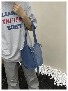 Vue détaillée du sac seau en denim porté en bandoulière de style minimaliste