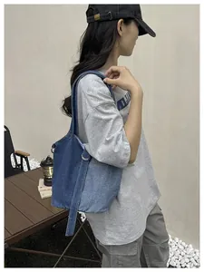 Vue latérale du sac seau en denim bicolore porté par un mannequin en extérieur.