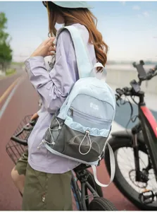 Lifestyle-detail van een lichtblauwe mini rugzak met kleurblokken gedragen door een fietser