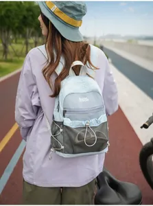 Lifestyle-foto van een vrouw met een lichtblauwe en grijze mini patchwork rugzak buiten