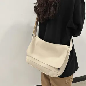 Minimalist cream white canvas messenger bag in workwear style shown on a model