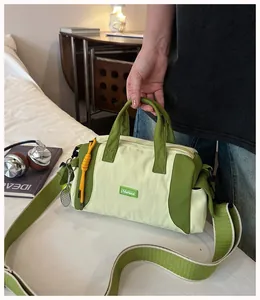 Detailansicht einer trendigen grünen Boston-Tasche aus Nylon mit Tennis-Thema-Anhänger