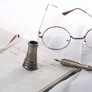 Primer plano de un portalápices de metal bronce vintage sobre un cuaderno con gafas