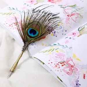 Primer plano de una pluma de pavo real vintage sobre una página de cuaderno decorada.