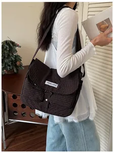Dettaglio di una grande borsa a tracolla in tela a scacchi indossata da una modella