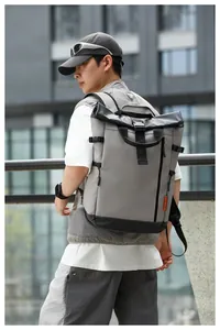 Man wearing a waterproof grey and black roll-top laptop backpack in urban setting