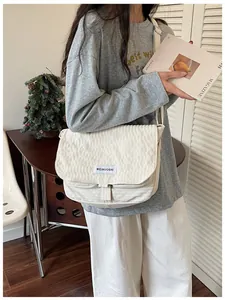 Dettaglio di una borsa messenger in tela bianca stile vintage con patta ed etichetta