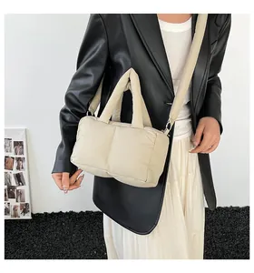 Detailed view of a beige puffy quilted tote bag held by a stylish female model