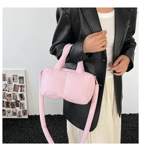 Pink quilted puffer tote bag with thick strap worn by model in a stylish leather jacket