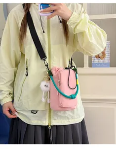 Close-up detail of a pink mini crossbody phone bag with green handle shown on a model
