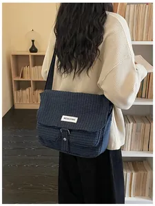 Vista posteriore di una grande borsa a tracolla in tela blu navy su un modello studentesco