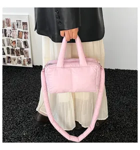 Close-up detail of a soft pink quilted puffer tote bag with a thick padded shoulder strap