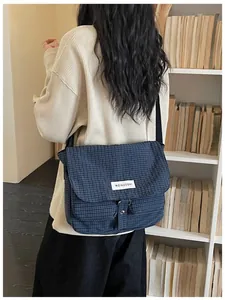 Borsa a tracolla in tela a scacchi blu scuro indossata da una studentessa a scuola.