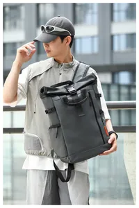 Outdoor lifestyle shot of a man wearing a dark grey roll-top waterproof laptop backpack