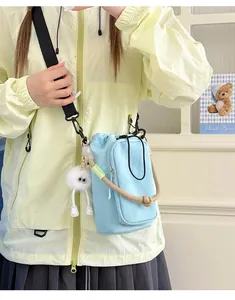 Close-up of a minimalist light blue crossbody bag worn with a light green jacket.
