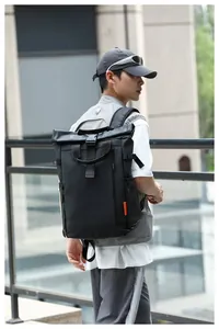 Back view of a man wearing a large black roll-top waterproof oxford cloth backpack