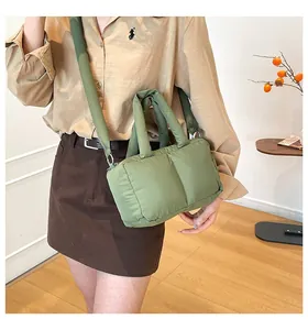 Detail view of a sage green puffer handbag and crossbody tote bag with padded texture