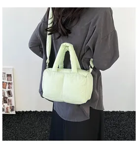 Back view of a light green puffy quilted crossbody tote bag worn by a model