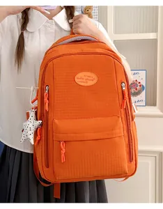 Close-up of large orange grid backpack for students with star charm and zip details