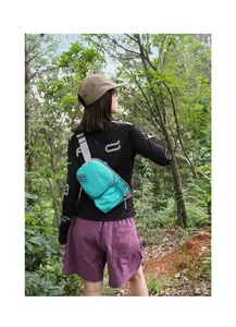 Vielseitige blaugrüne Outdoor-Lauftasche, getragen von Wanderin auf dem Waldweg