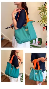 Model carrying a large teal waterproof shopping bag with orange contrast straps and patch.