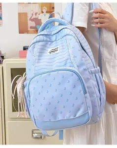 Light blue backpack with stripes and butterfly patterns worn by a student model.