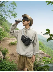 Asiatisches Modell mit schwarzer Outdoor-Brusttasche und Trinkflaschenhalter beim Wandern.