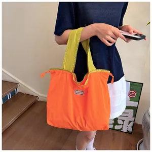 Detailed view of orange foldable shopping bag with green straps and drawstrings