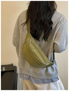 Detailed back view of an olive green street style fanny pack worn crossbody on a gray sweatshirt