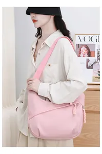 Detail of a stylish pink oxford cloth hobo shoulder bag worn by a fashion model.