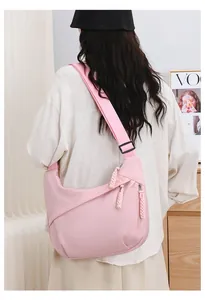 Back view of a stylish pink oxford crescent crossbody bag worn by a female model.