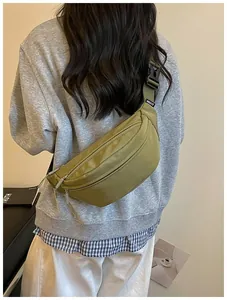 Trendy olive green crossbody fanny pack shown in a casual lifestyle street setting