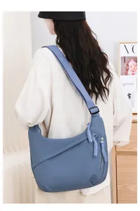 Detailed view of a stylish blue oxford crossbody bag for women worn by an Asian model