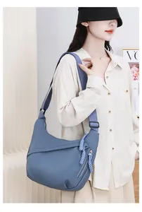 Detailed shot of a stylish blue oxford cloth crossbody bag worn by a female model