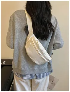 Cream white minimalist sling bag worn cross-body over a casual grey sweatshirt style