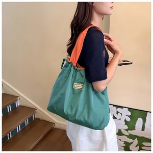 Large teal and orange waterproof drawstring tote bag shown in a lifestyle setting