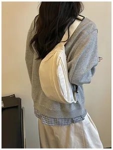 Cream nylon crossbody fanny pack worn by model in casual street style outfit.