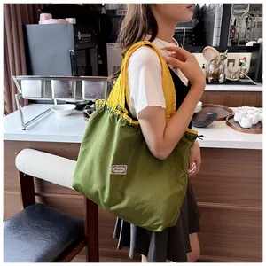 Detail shot of the large green and yellow drawstring shopping bag carried on shoulder.