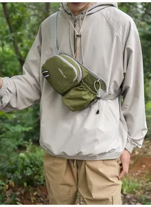 Grüne Outdoor-Sport-Brusttasche mit Flaschenhalter, getragen von einem Modell beim Wandern